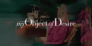 My Object of desire: Elegant model wearing a red couture dress, sitting in a vintage setting with a sewing machine in the background.