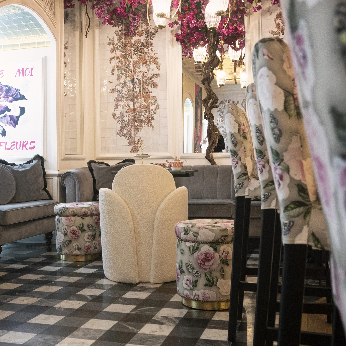 Oh-Lá-Lá chair by KKbyKoket in a floral-themed coffee shop, surrounded by patterned ottomans & bar stools.
